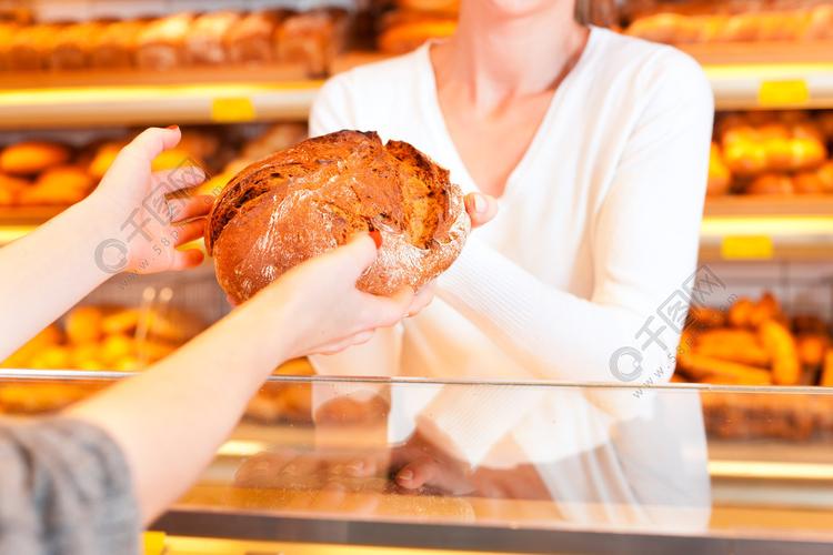 女面包师或女售货员在她的面包店与一位女性顾客和新鲜糕点或烘焙产品