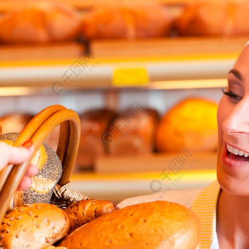 女面包师或女售货员在她的面包店与一位女性顾客和新鲜糕点或烘焙产品